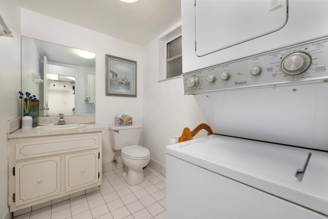 bathroom featuring vanity, stacked washing maching and dryer, tile patterned floors, and toilet