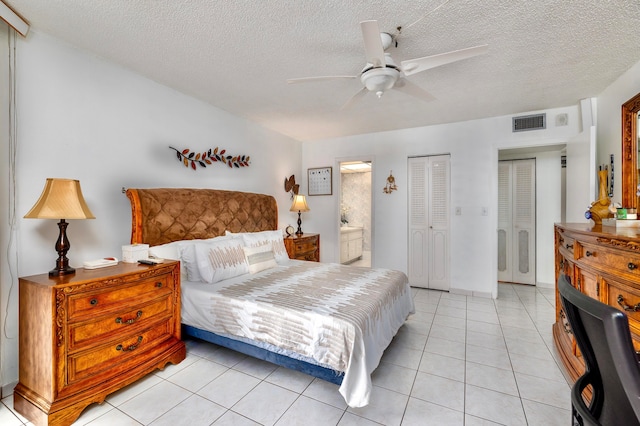 tiled bedroom with a textured ceiling, ensuite bath, and ceiling fan