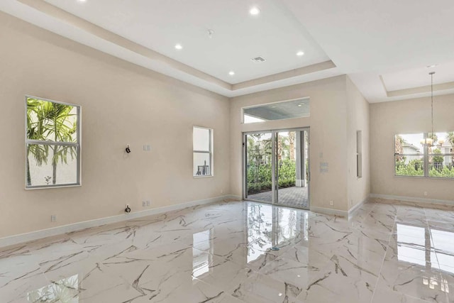 interior space with a notable chandelier, a raised ceiling, and a wealth of natural light