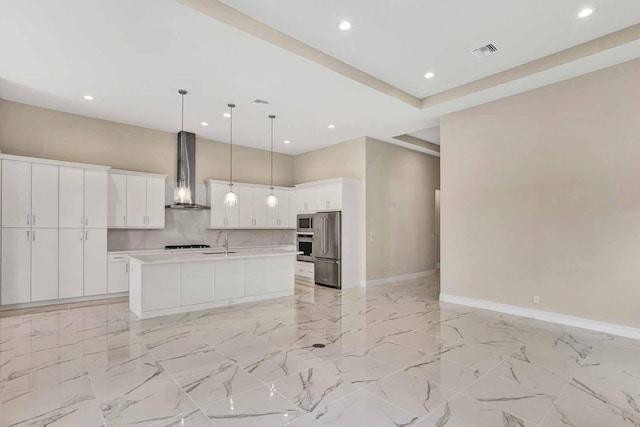 kitchen with wall chimney range hood, white cabinets, a kitchen island with sink, and stainless steel appliances