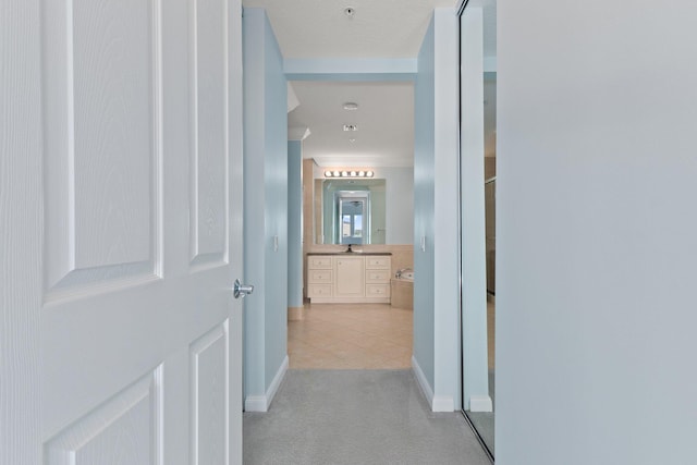 hallway with light tile patterned flooring and sink