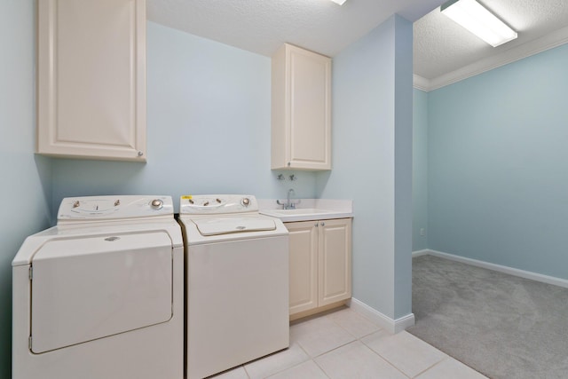 washroom with ornamental molding, a textured ceiling, cabinets, washing machine and dryer, and light carpet