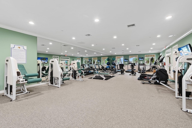 exercise room featuring ornamental molding and light carpet