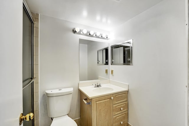 bathroom featuring a shower with door, vanity, and toilet