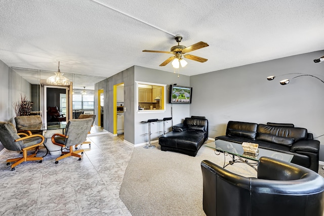 living room featuring a textured ceiling and ceiling fan with notable chandelier