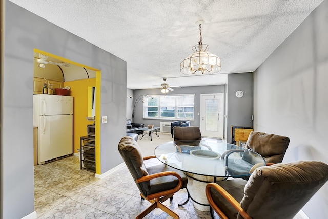 dining room featuring ceiling fan with notable chandelier and a textured ceiling