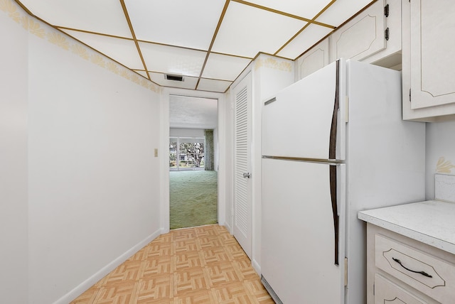 kitchen featuring light parquet flooring, white cabinetry, and white refrigerator