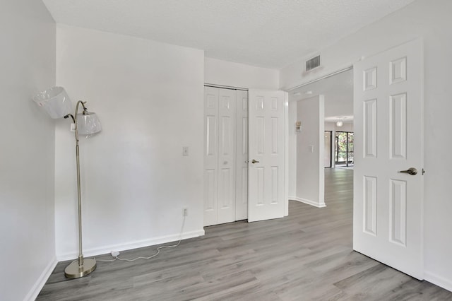 unfurnished bedroom with a textured ceiling, light hardwood / wood-style flooring, and a closet