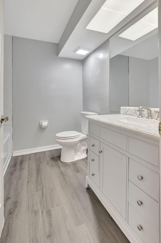 full bathroom with  shower combination, vanity, hardwood / wood-style floors, and toilet