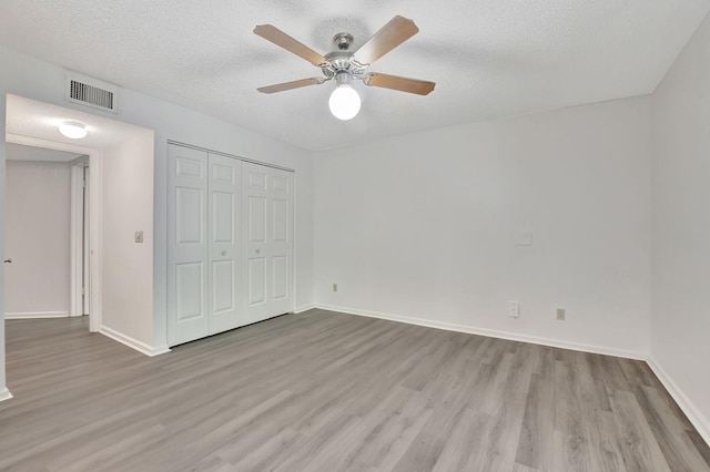 unfurnished bedroom with a closet, light wood-type flooring, ceiling fan, and a textured ceiling