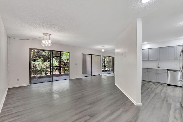 interior space with an inviting chandelier, light wood-type flooring, a textured ceiling, and sink