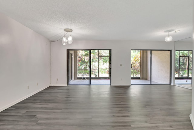 unfurnished room with a textured ceiling, dark hardwood / wood-style floors, and a notable chandelier