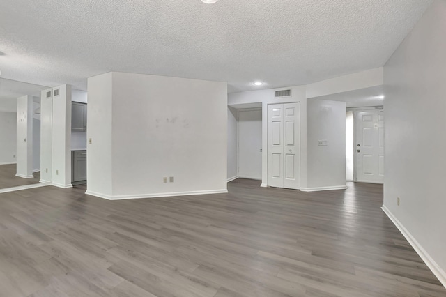 unfurnished living room featuring a textured ceiling and dark hardwood / wood-style floors