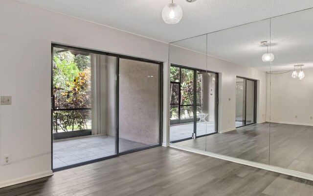 unfurnished room featuring hardwood / wood-style floors, a textured ceiling, a chandelier, and a healthy amount of sunlight