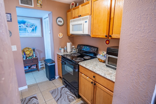 kitchen with black electric range oven, light tile patterned flooring, and light stone countertops