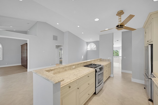 kitchen with light tile patterned flooring, cream cabinets, light stone countertops, high vaulted ceiling, and appliances with stainless steel finishes