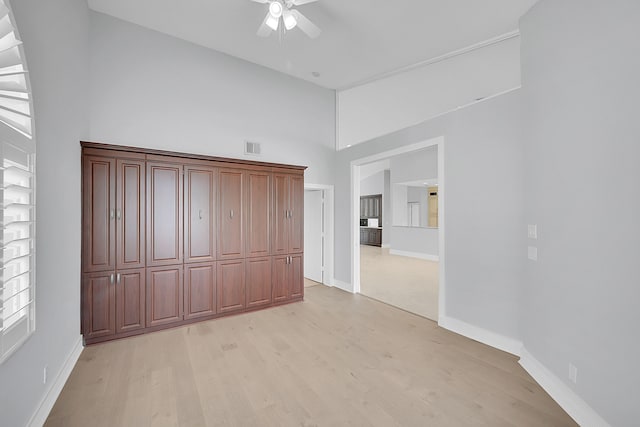 unfurnished bedroom with ceiling fan, light hardwood / wood-style flooring, and a towering ceiling