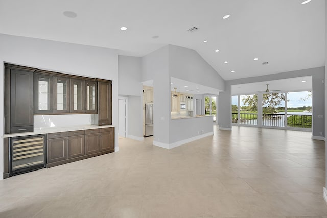 unfurnished living room featuring ceiling fan, wine cooler, high vaulted ceiling, and light tile patterned flooring