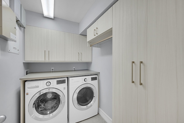 laundry area with independent washer and dryer and cabinets