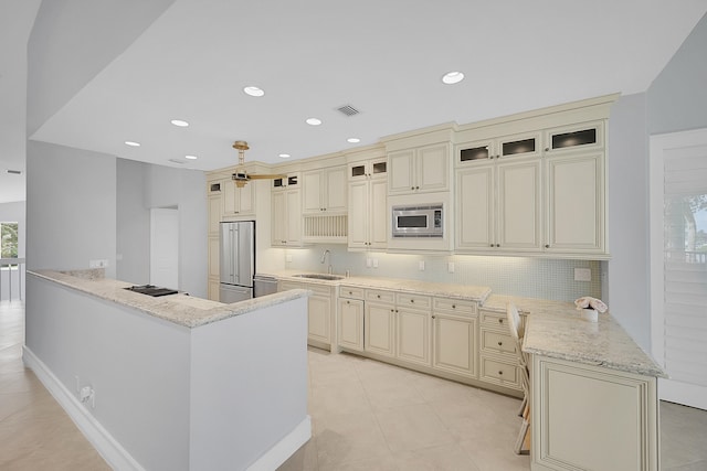 kitchen featuring cream cabinets, stainless steel appliances, sink, and kitchen peninsula