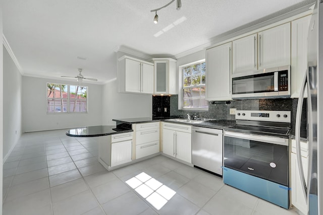 kitchen featuring kitchen peninsula, appliances with stainless steel finishes, white cabinets, and a wealth of natural light