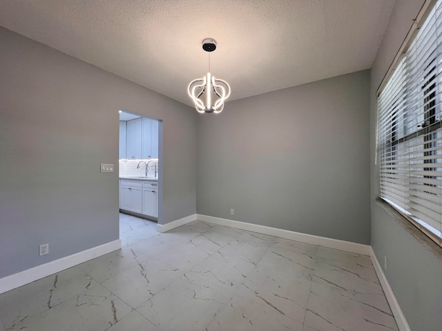 unfurnished room featuring a textured ceiling, an inviting chandelier, and sink