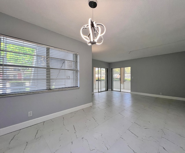 unfurnished room with a textured ceiling and an inviting chandelier