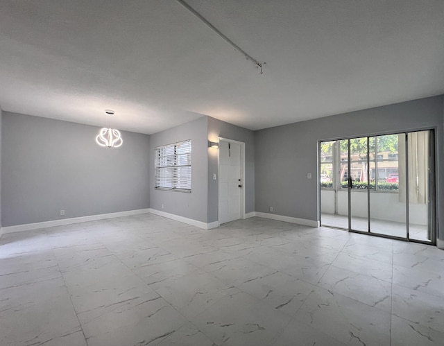 spare room with an inviting chandelier and a wealth of natural light