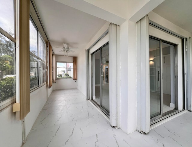 unfurnished sunroom with ceiling fan