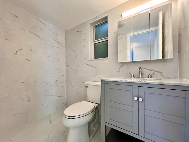 bathroom featuring vanity, tile walls, and toilet