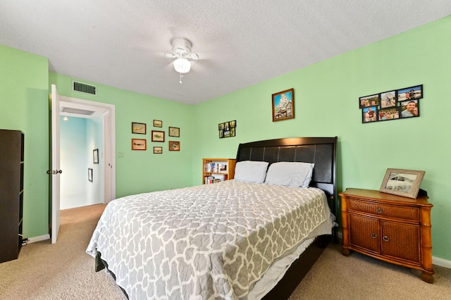 bedroom with a textured ceiling, light colored carpet, and ceiling fan