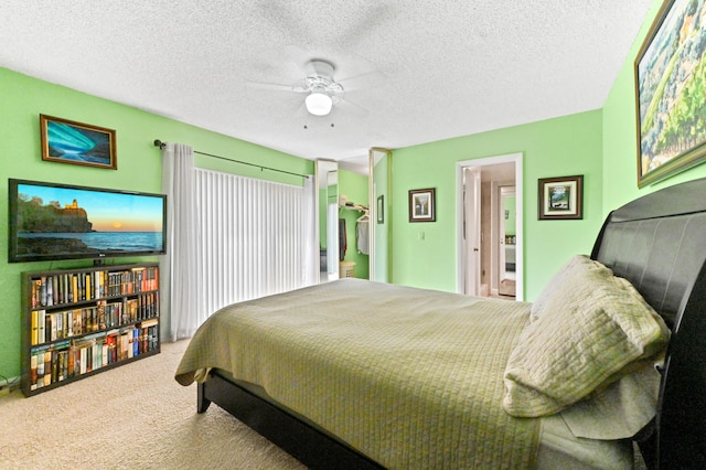 bedroom with carpet flooring, a textured ceiling, ensuite bath, and ceiling fan