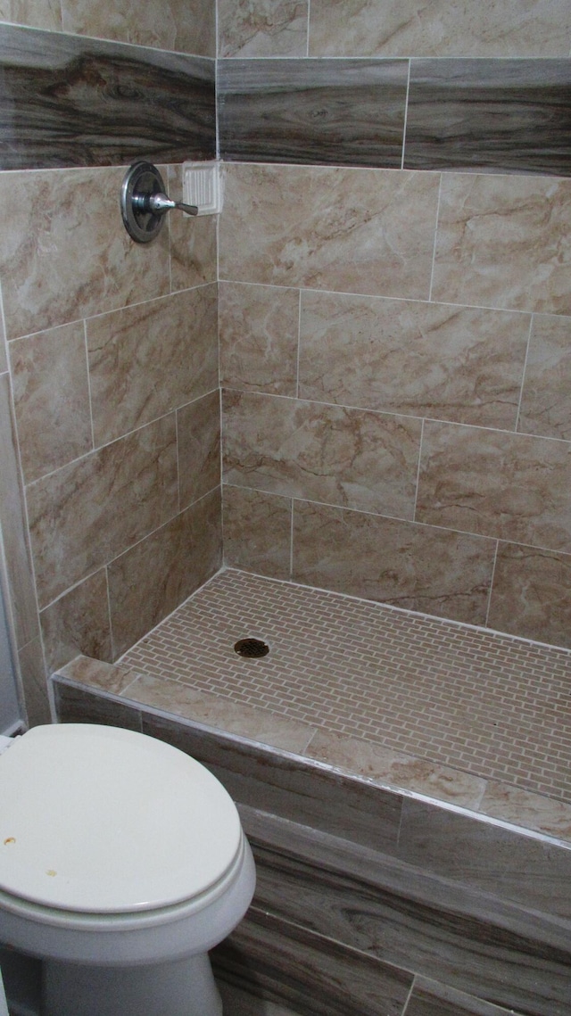 bathroom featuring a tile shower and toilet