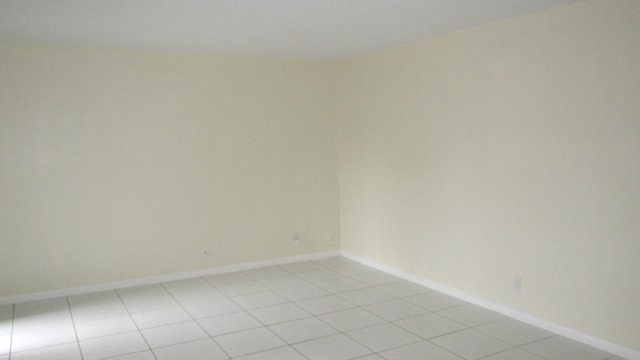 spare room with baseboards and light tile patterned floors