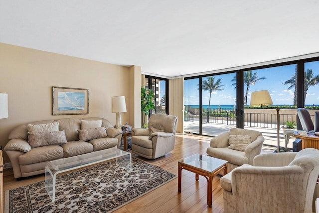 living room with a water view, light hardwood / wood-style flooring, and floor to ceiling windows