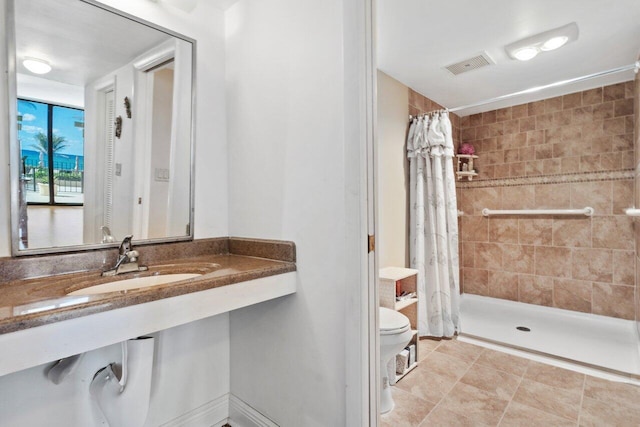 bathroom featuring a shower with shower curtain, toilet, sink, and tile patterned floors