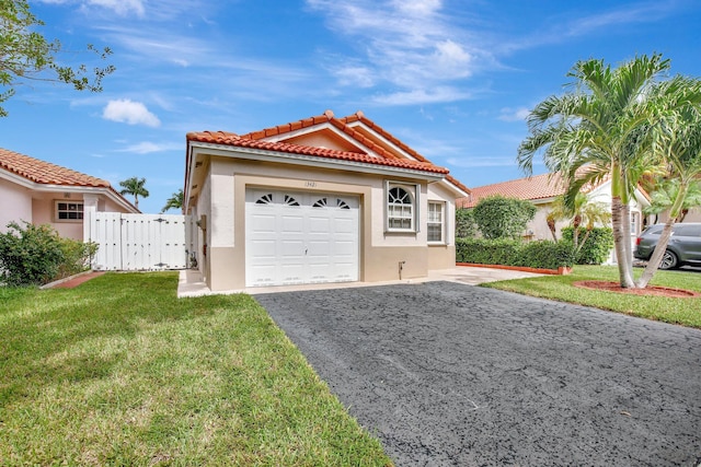 mediterranean / spanish home featuring a garage and a front lawn