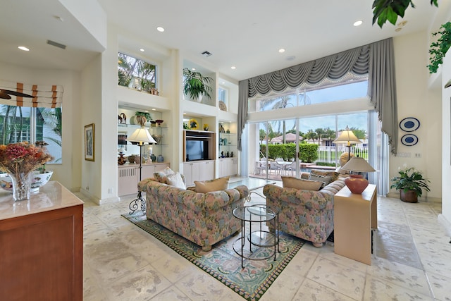 living room with a towering ceiling and built in features