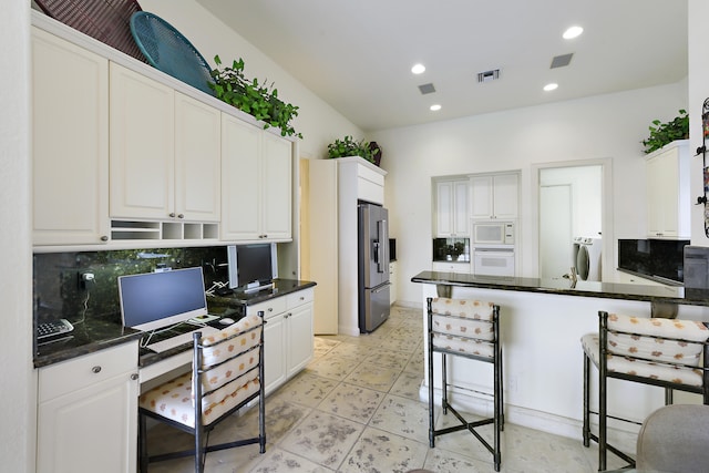 kitchen featuring decorative backsplash, dark stone counters, sink, dishwasher, and kitchen peninsula