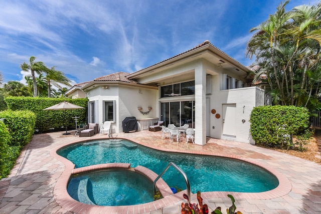 rear view of property featuring a swimming pool with hot tub and a patio