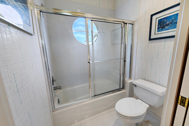 bathroom featuring bath / shower combo with glass door, tile patterned floors, a wealth of natural light, and toilet