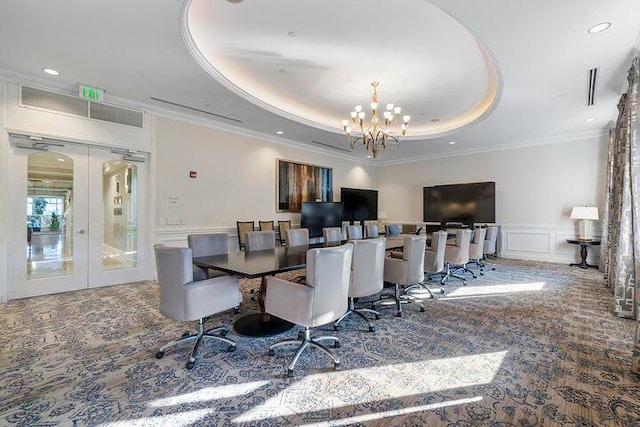 carpeted dining area with ornamental molding, a tray ceiling, and a chandelier