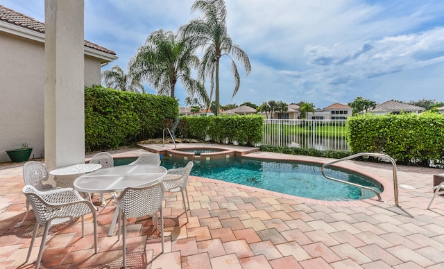 view of swimming pool featuring an in ground hot tub, a water view, and a patio area