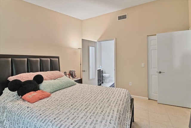 bedroom with light tile patterned flooring, a towering ceiling, and ensuite bathroom