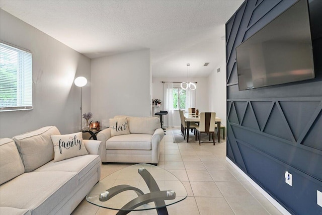 living room featuring plenty of natural light, a chandelier, light tile patterned floors, and a textured ceiling