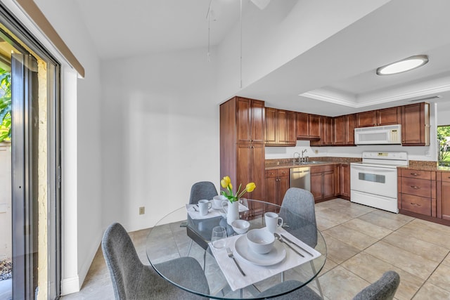 interior space with a raised ceiling, sink, light tile patterned floors, and white appliances