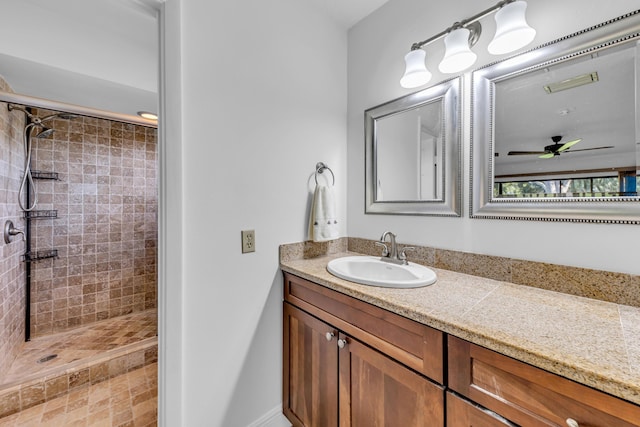 bathroom featuring ceiling fan, tiled shower, and vanity