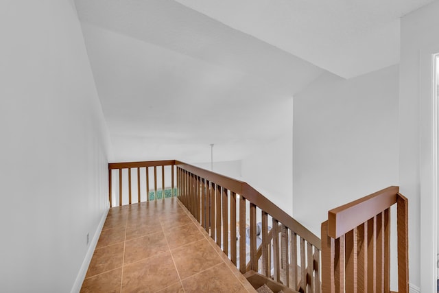 hallway featuring tile patterned flooring and lofted ceiling