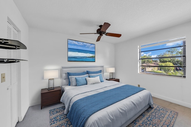 bedroom featuring ceiling fan, light colored carpet, and a textured ceiling