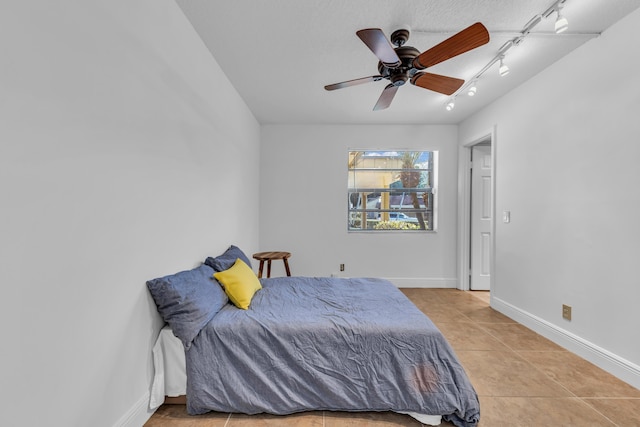 bedroom featuring rail lighting, ceiling fan, and light tile patterned flooring